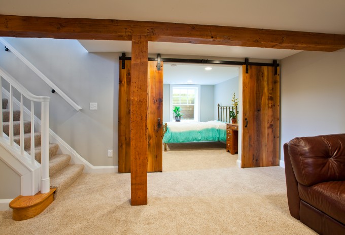 Sliding barn doors bring both living space and bedroom space in Minneapolis basement remodel.